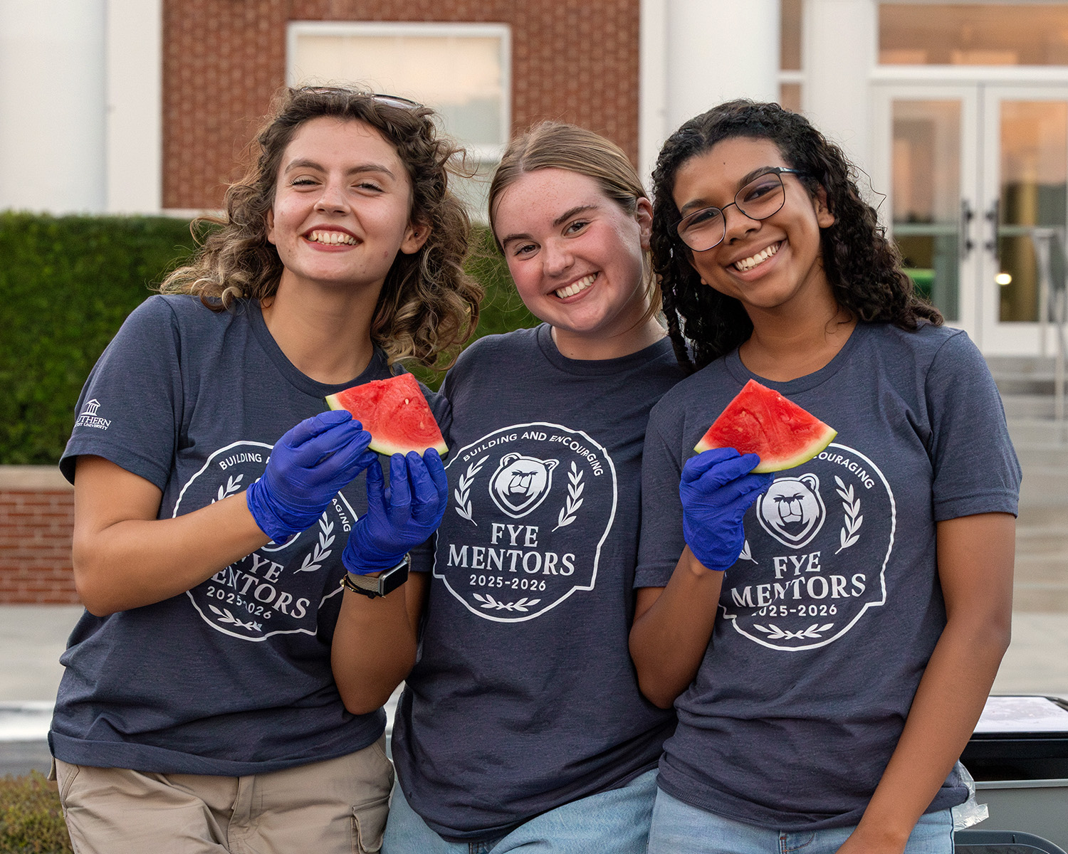 three Southern Adventist University students hand out watermelon at the annual welcome back party