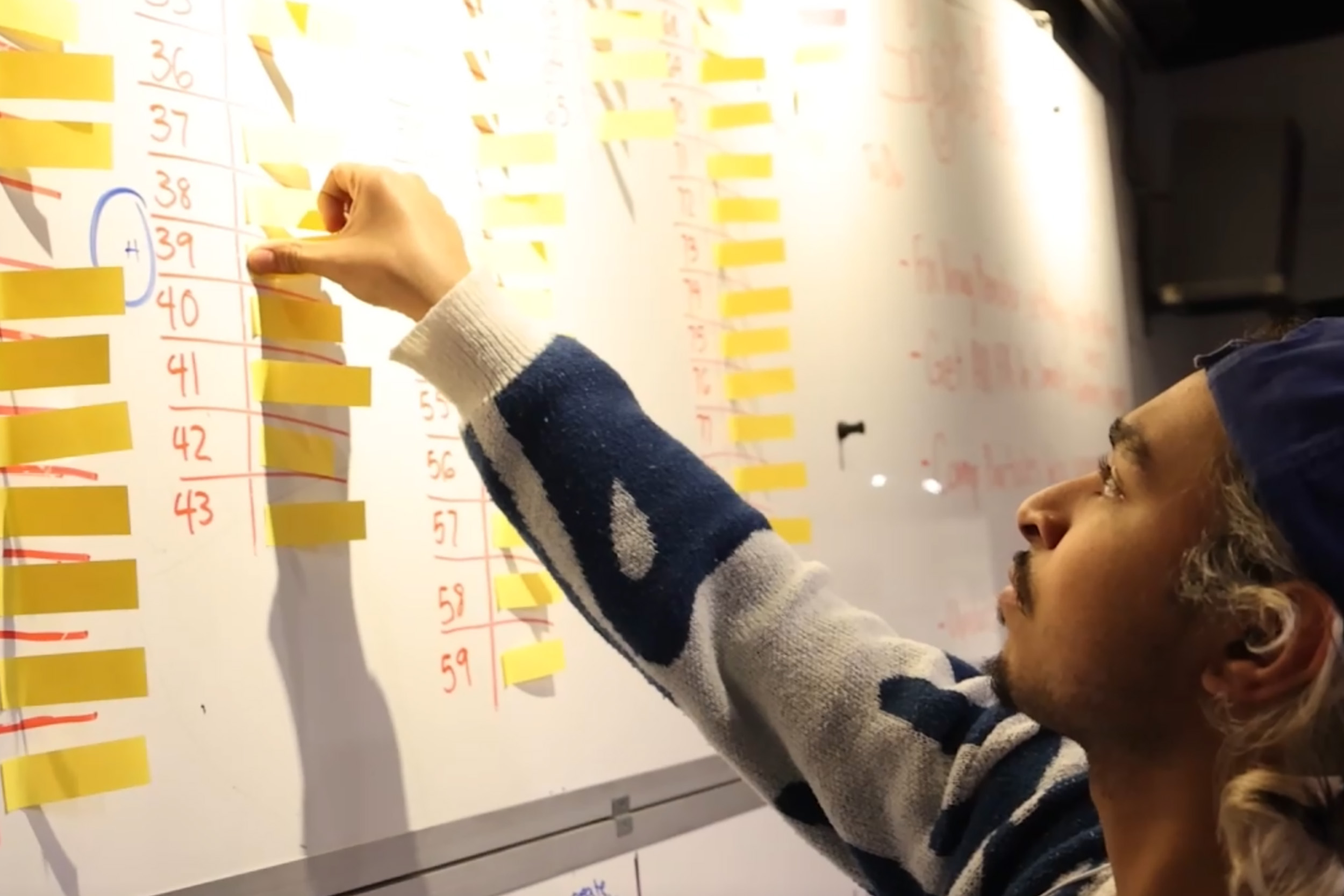 student placing sticky notes on a white board