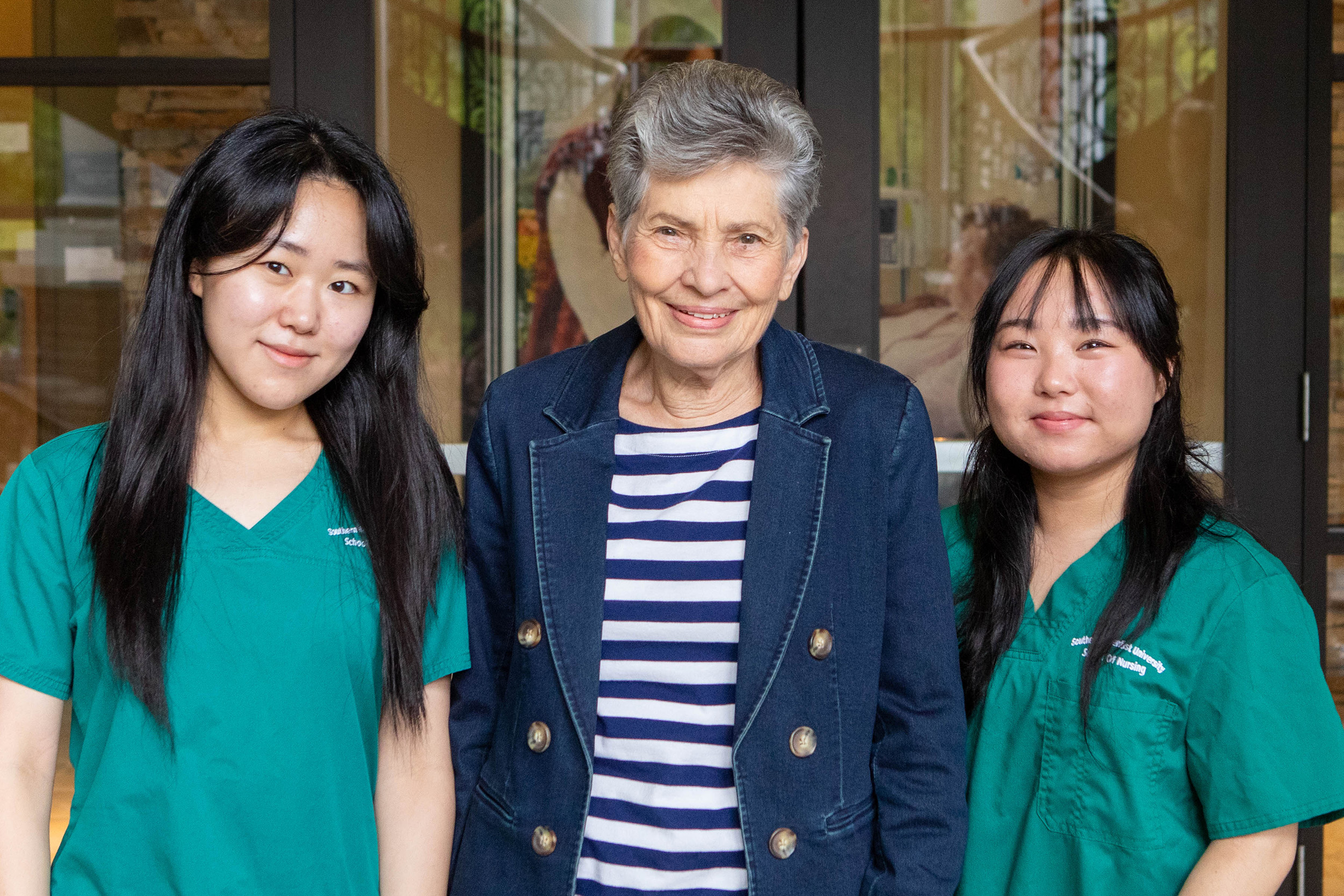 Two Southern Adventist University nursing students stand beside community member Barbara Smith