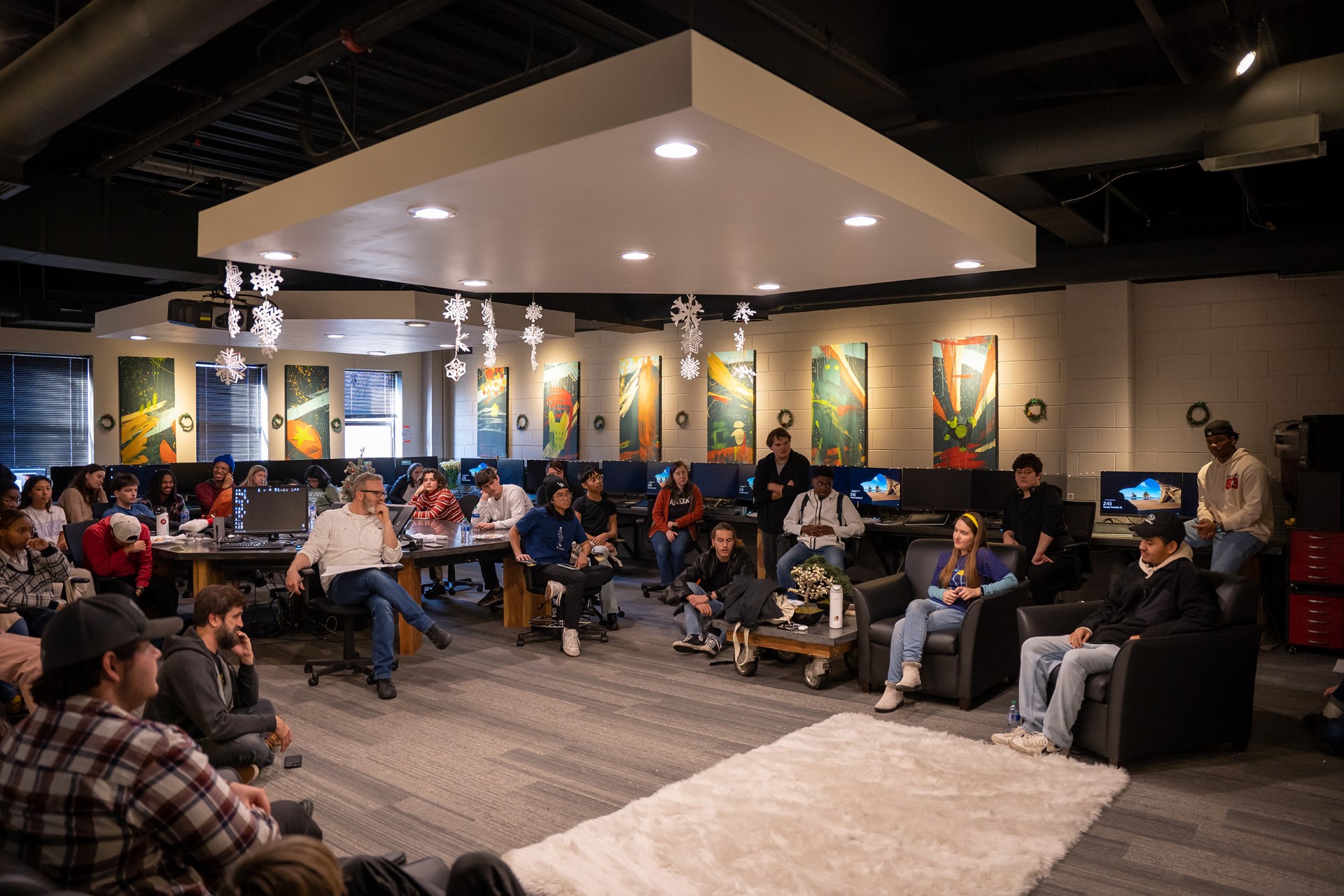 A group of students listen to animation alumni speak to them. 